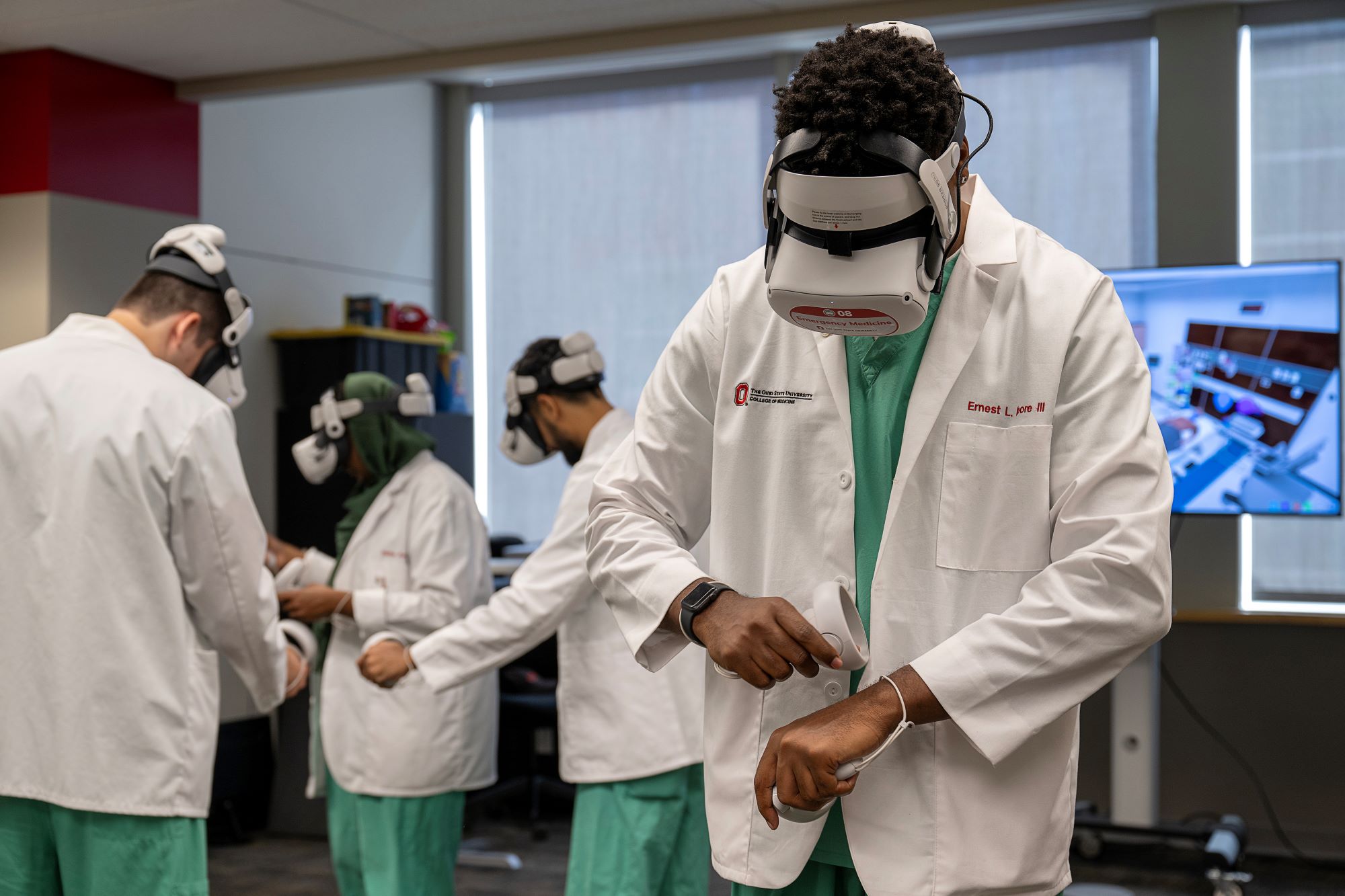 Students wearing scrubs and lab coats, preparing to use their individual virtual reality headsets.